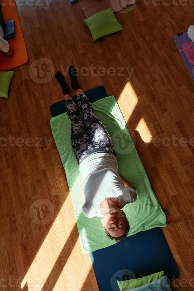 Senior woman practicing stretching and meditation on the floor, focusing on proper alignment and relaxation. photo
