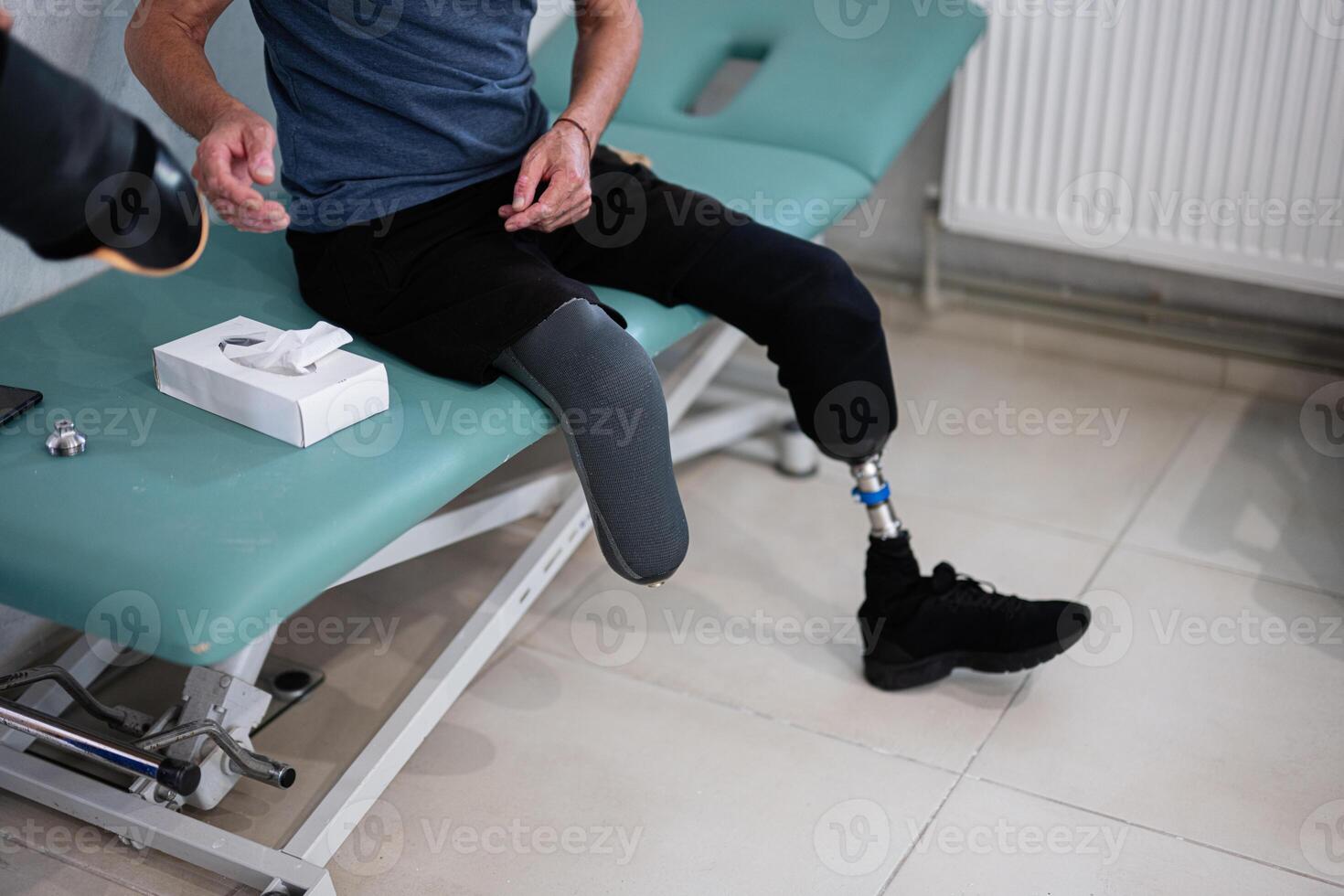 Man with prosthetic leg sitting on examination table photo