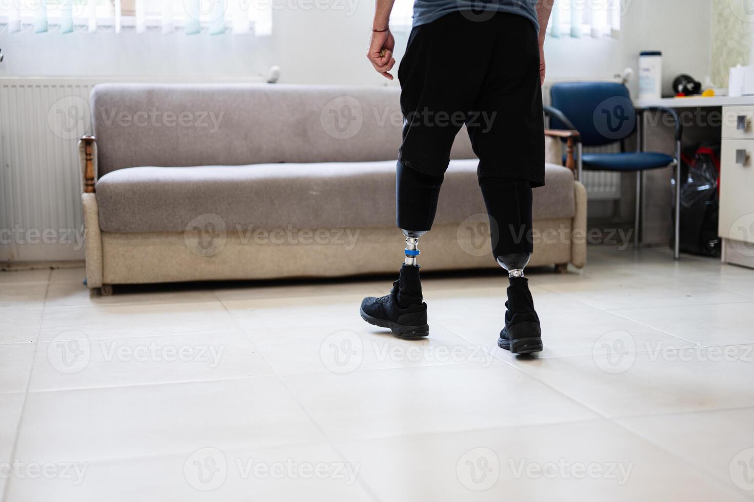 Person with prosthetic legs walking in a living room setting photo