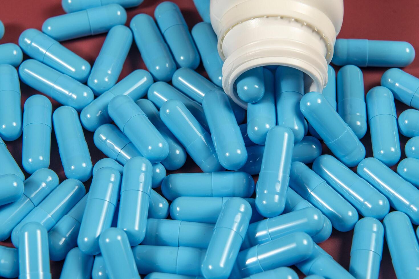 blue medicine capsules and white bottle photo