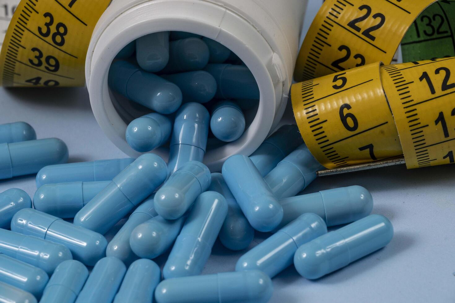 bottle of pills, some of which spilled onto a light blue surface photo