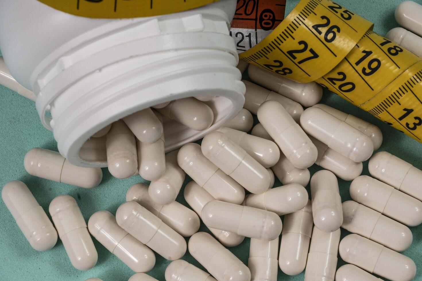bottle of pills, some of which spilled onto a light blue surface photo