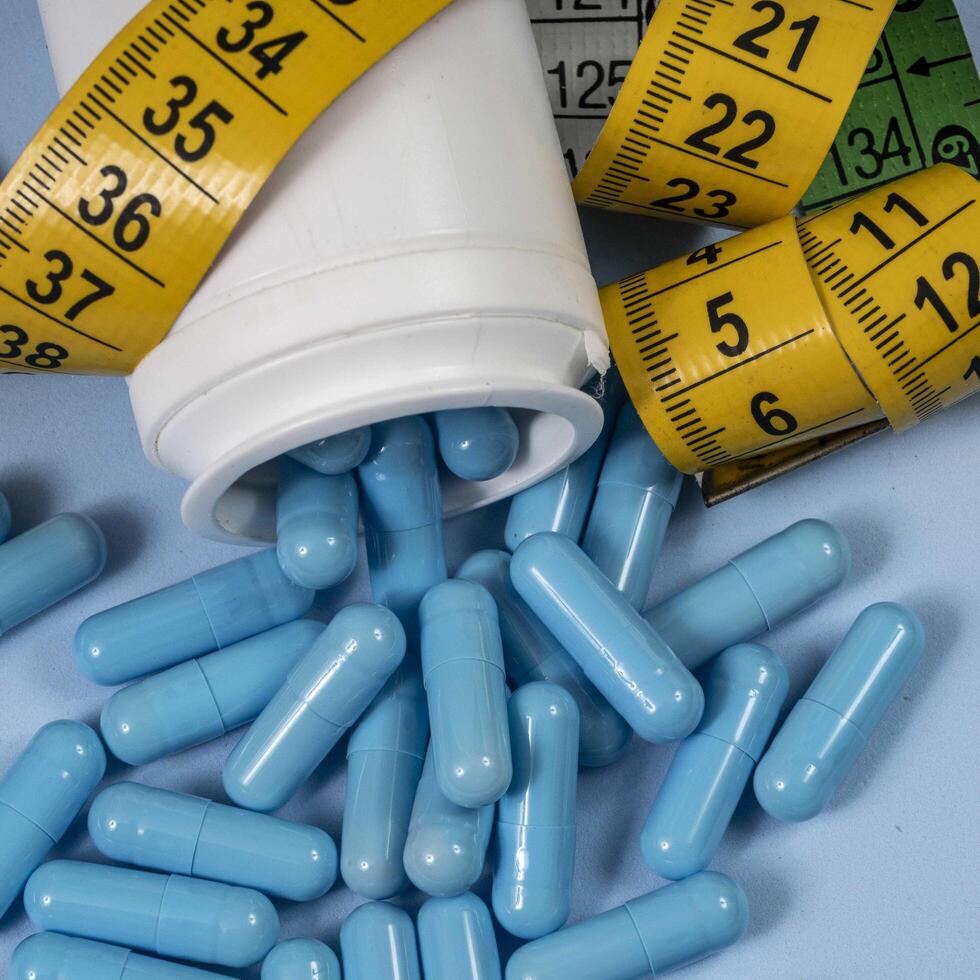 bottle of pills, some of which spilled onto a light blue surface photo