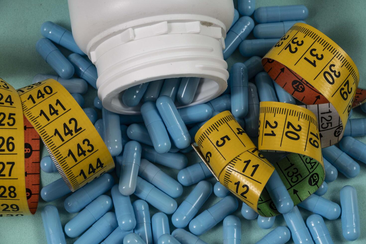 bottle of pills, some of which spilled onto a light blue surface photo