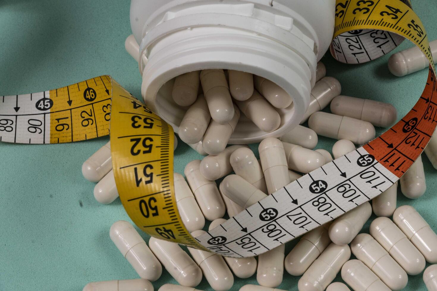 bottle of pills, some of which spilled onto a light blue surface photo