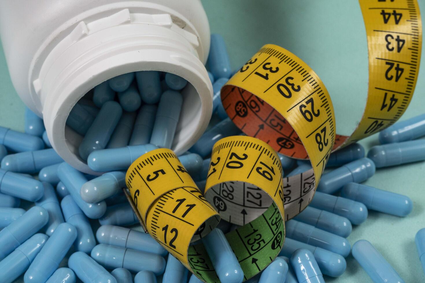bottle of pills, some of which spilled onto a light blue surface photo