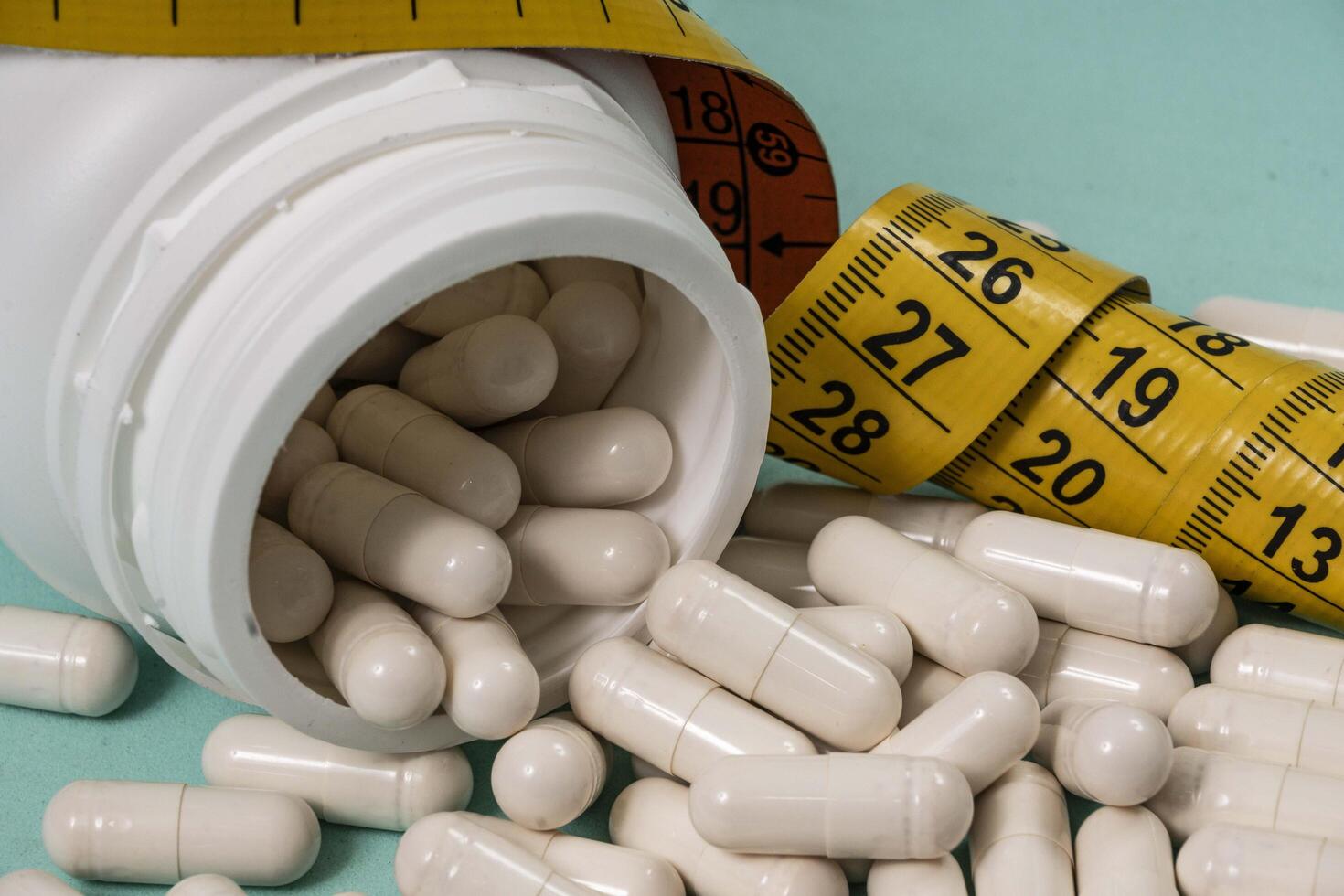 bottle of pills, some of which spilled onto a light blue surface photo