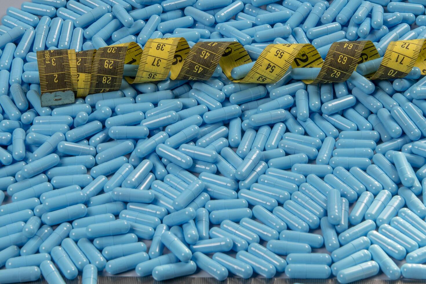 Blue weight loss pills and measuring tape symbolizing slimming photo