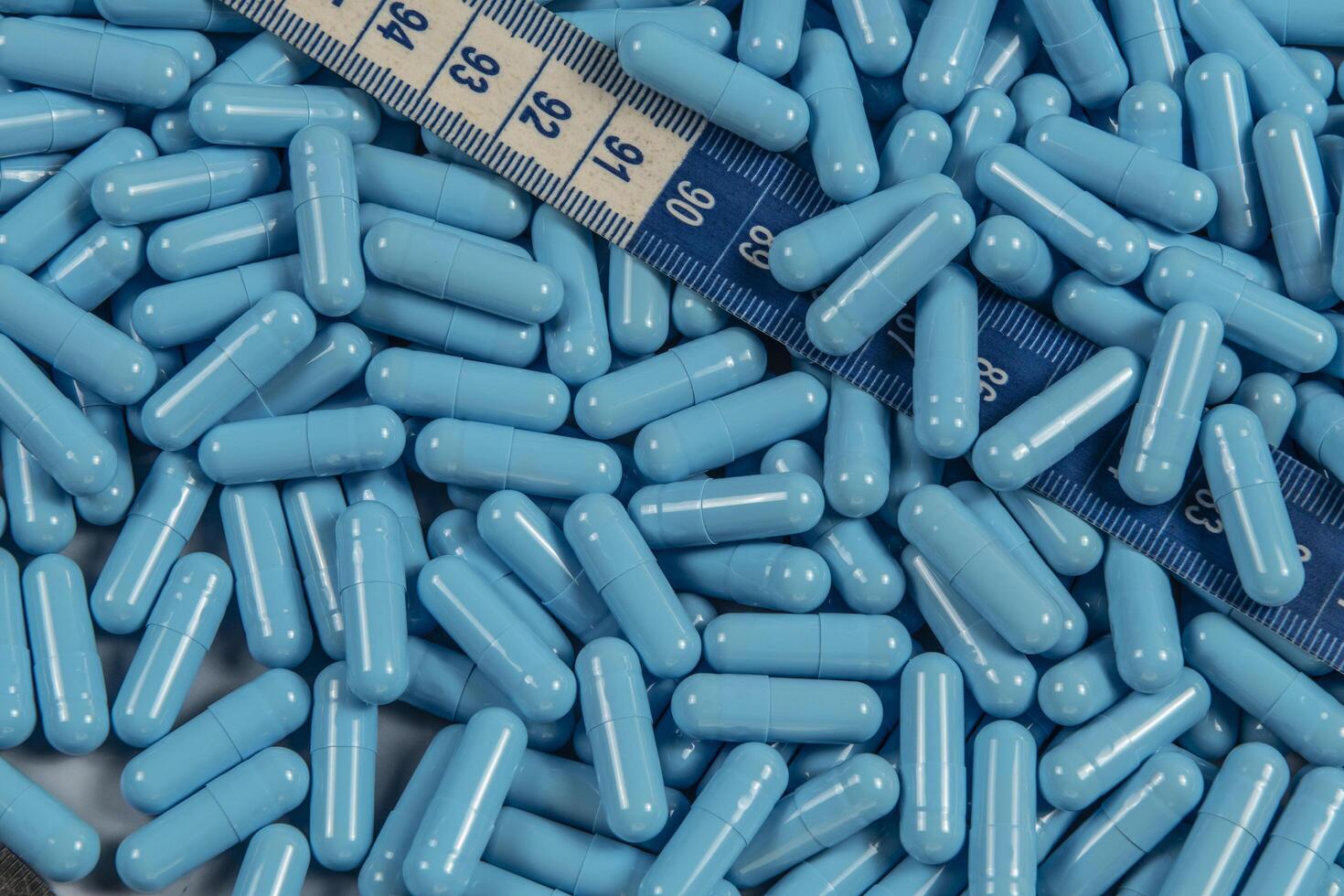 Blue weight loss pills and measuring tape symbolizing slimming photo