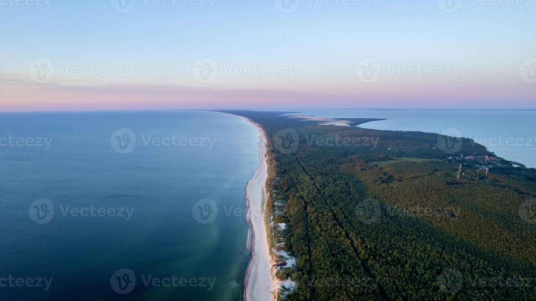 Curonian Spit National Park at sunset, aerial shot. A narrow and long sandy strip of land separating the Curonian Lagoon from the Baltic Sea. Forest and sea. Drone view photo
