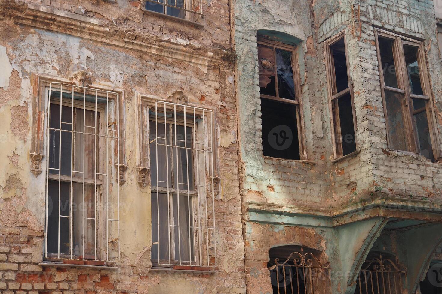An Abandoned Building featuring a Weathered Facade adorned with Iron Grills and Details photo