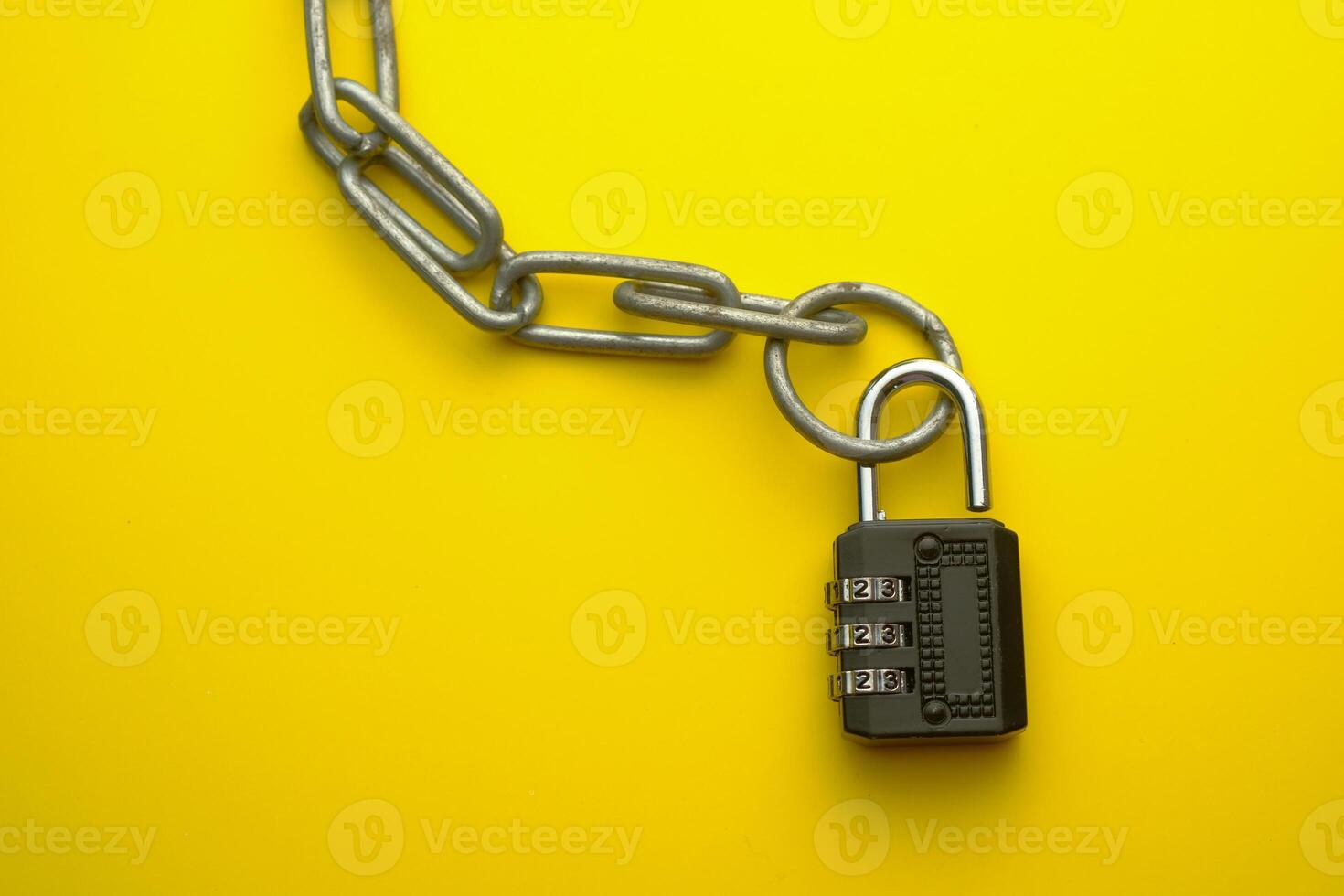 A combination lock is displayed on a sturdy metal chain, set against a bright yellow background photo