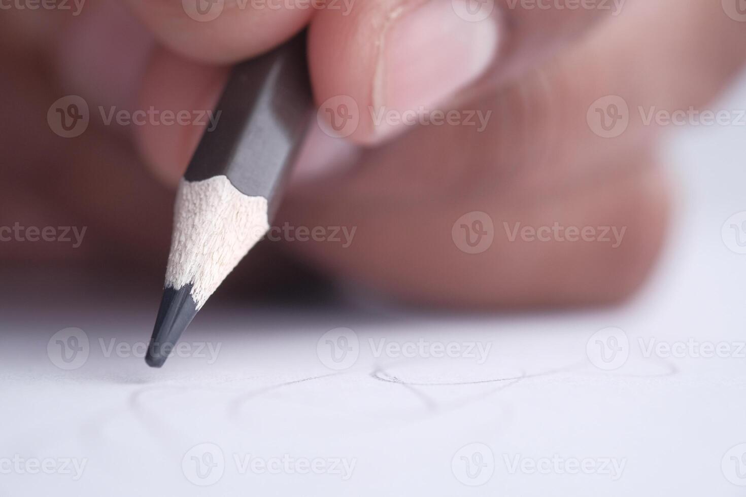 A closeup view of a hand gripping a pencil, poised over paper, ready for sketching activities photo
