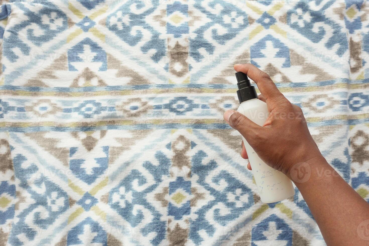 Gently and skillfully hand spraying a liquid onto a beautifully designed decorative fabric pattern photo
