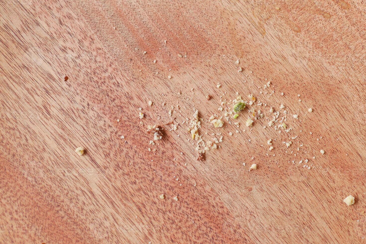 CloseUp View of Tiny Crumbs Scattered Across a Wooden Kitchen Surface photo