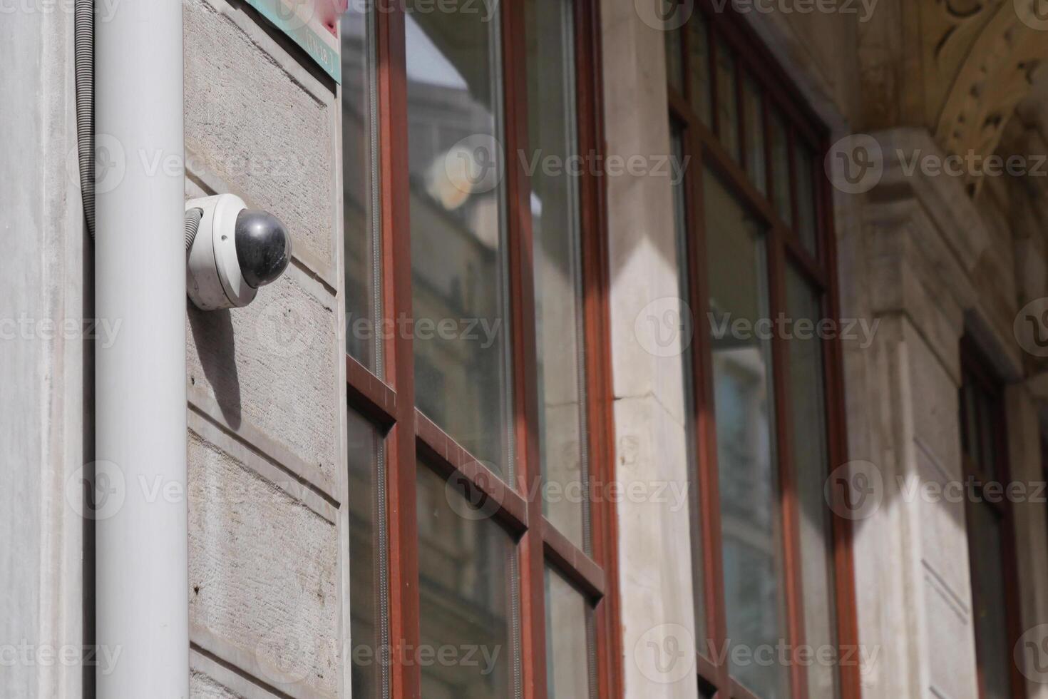 A surveillance camera has been installed on the exterior of the building featuring reflections photo