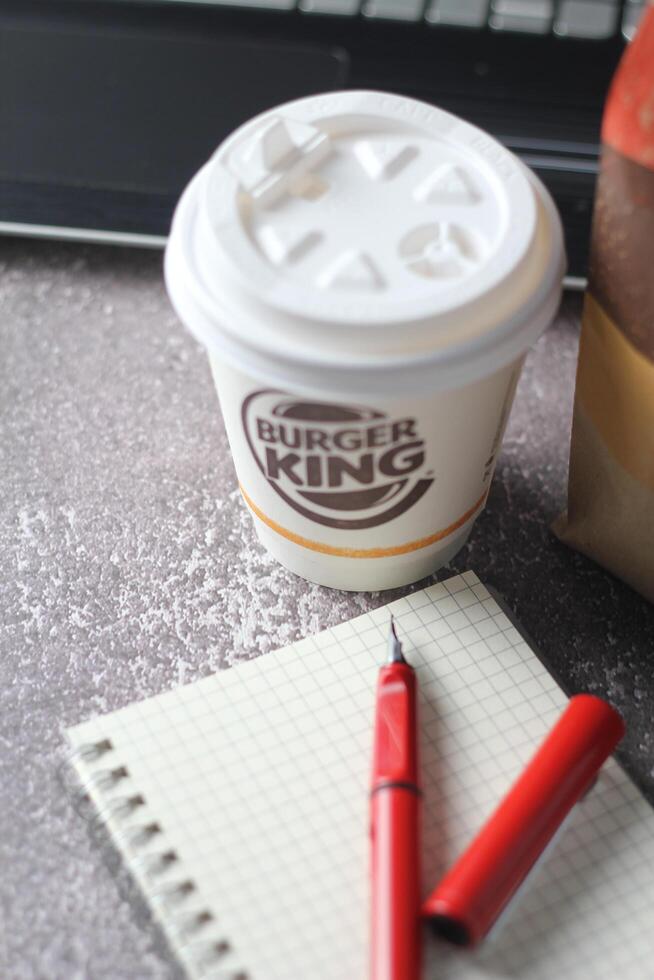 WASHINGTON - USA - August 17, 2024 - A Burger King coffee cup sits on a desk, next to a notebook and pen. photo