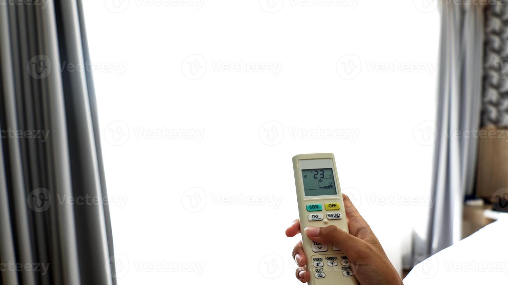 Woman Operating Remote Controller on Air Conditioner Inside the Room photo