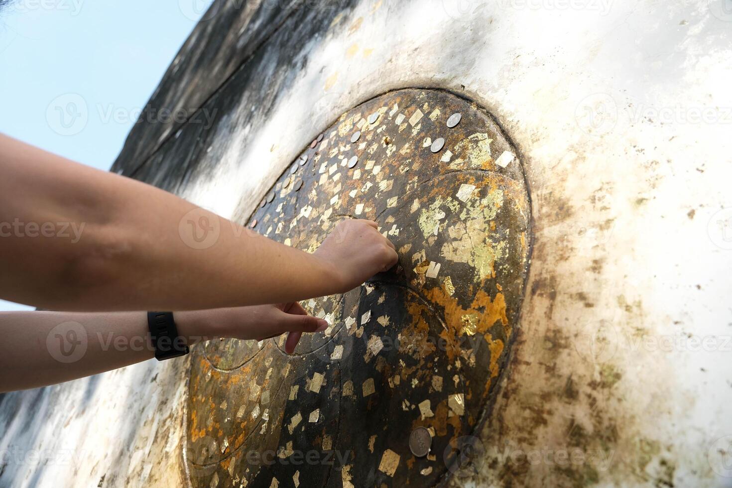 Someone Buddhist Gold leaf is being attached to the soles of feet Reclining Buddha statue. photo