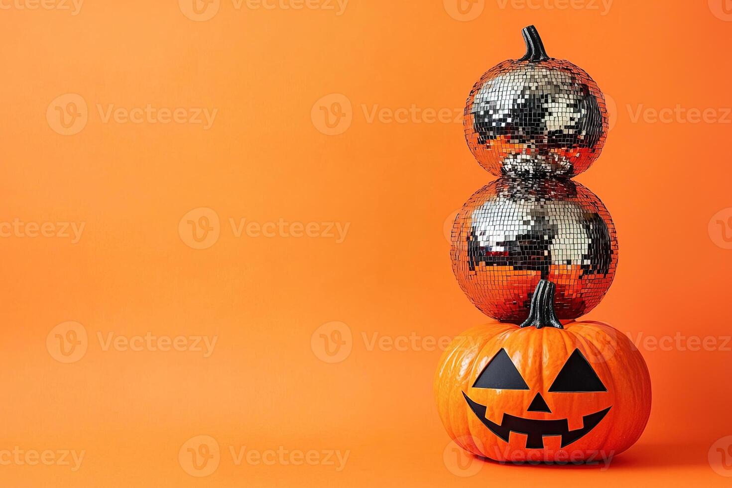 stack of Halloween carved pumpkin and pumpkins made from a mirror disco ball on an orange background with copy space photo