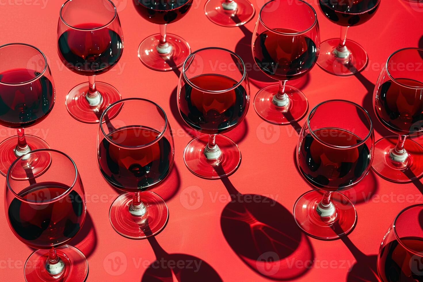 stylish pattern wine glasses with red wine on red background with bright sunlight, shadows and reflections photo