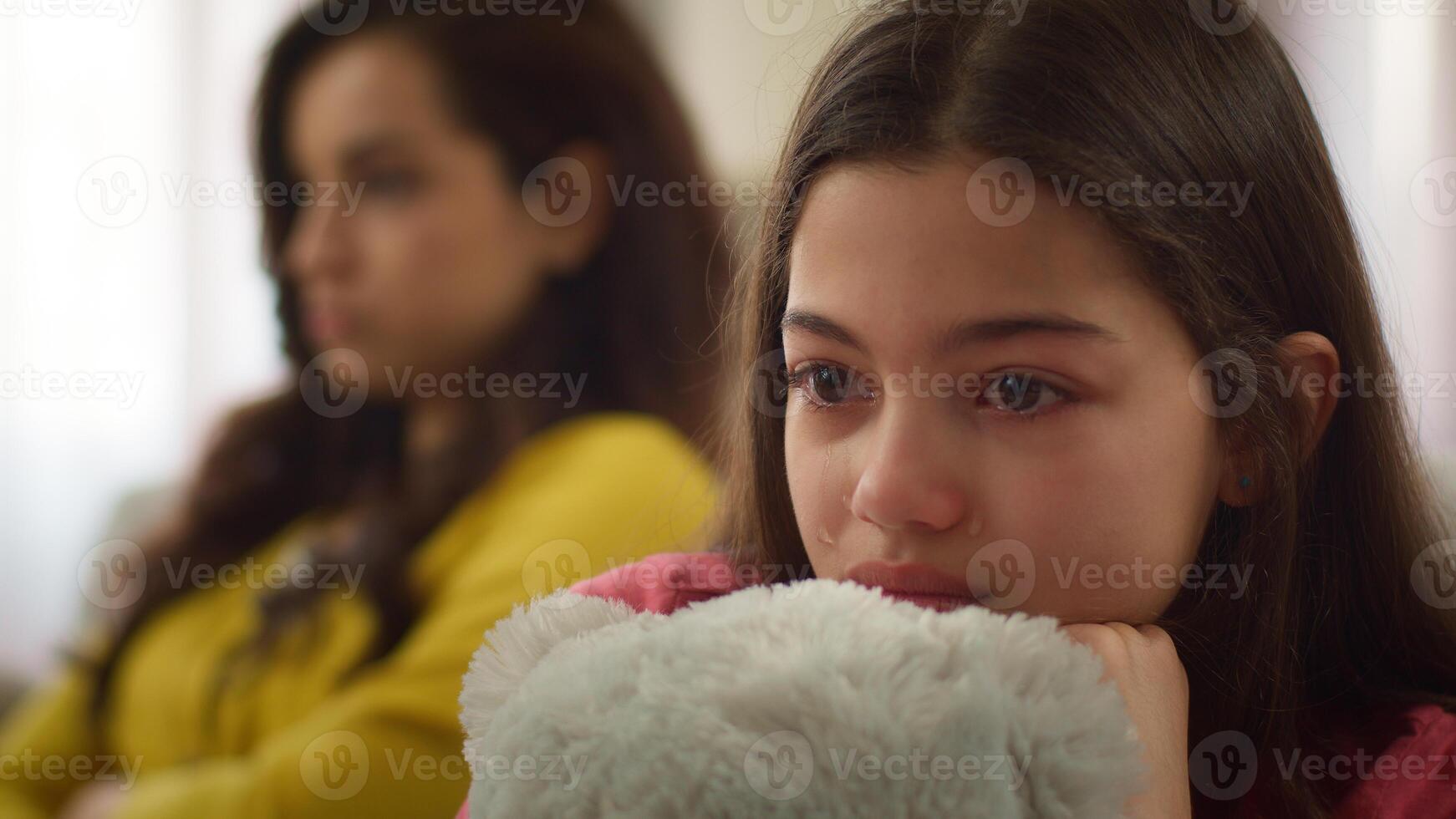 Family abuse conflict close up sad crying Caucasian little girl child kid daughter cry sitting with mad angry offended woman female mother babysitter quarrel argument trouble punishment indoors home photo