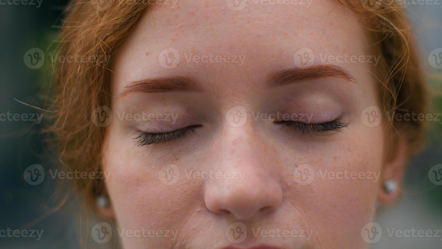 Close up beautiful smiling young Caucasian ginger woman face female lady girl slowly wide opening bright blue eyes looking camera outside city urban street. Clear vision makeup eyesight ophthalmology photo