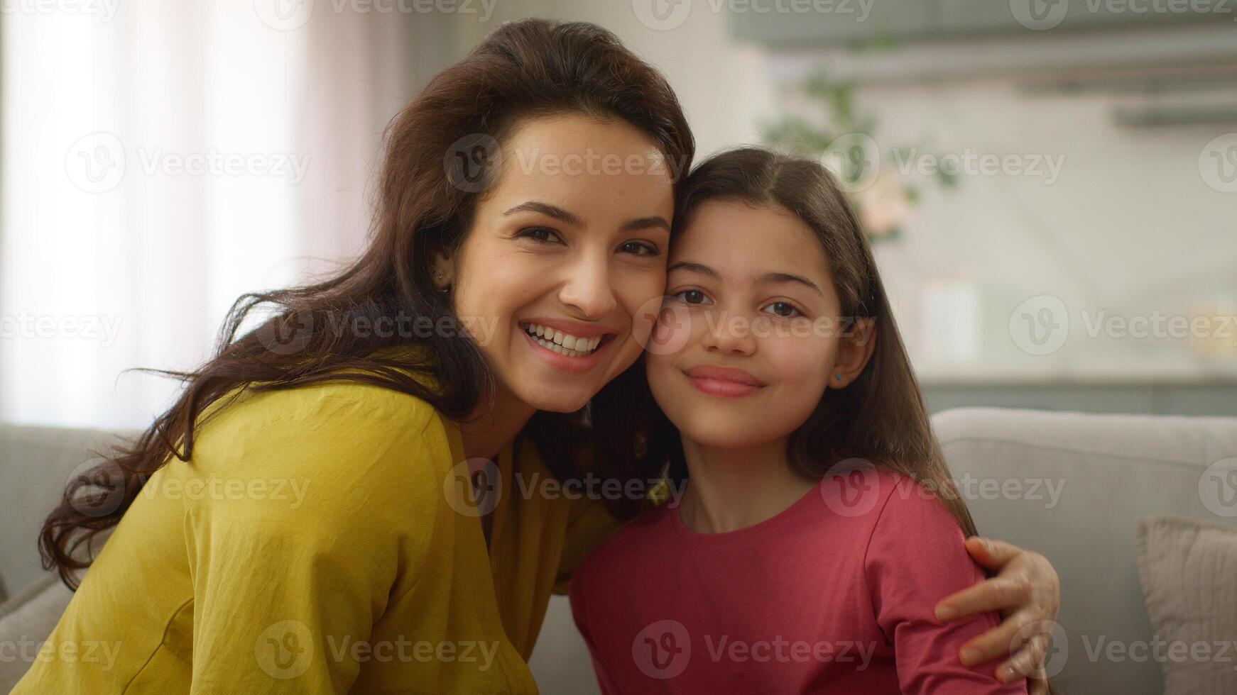 Cute love moment family bonding Caucasian woman female mother touching forehead cuddling with little girl preschool child daughter kid hugging on sofa embracing hug motherhood at home cozy apartment photo