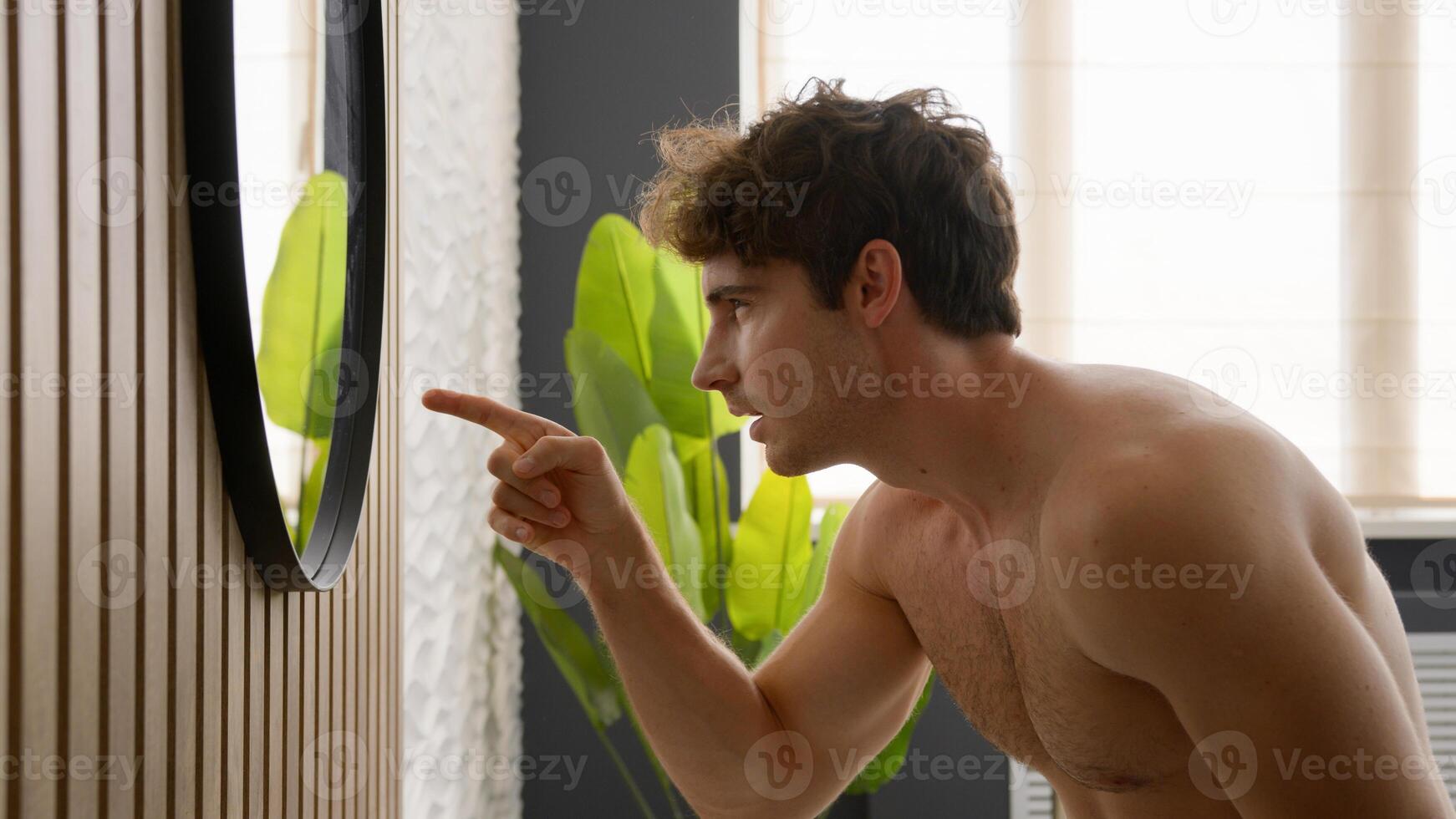 Millennial naked Caucasian man looking at mirror male check hair style baldness dandruff hairstyle hairdo mask care shampoo cosmetics morning beauty routine procedure guy pointing finger reflection photo