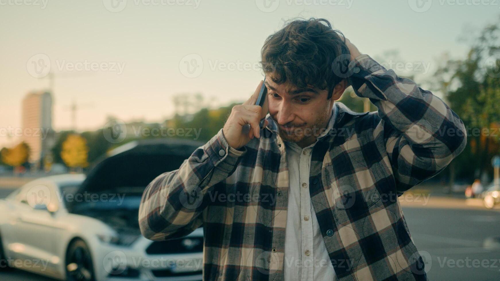 Worried stressed man driver Caucasian guy talk mobile phone calling car service engine problem stand on road outdoors broken car background vehicle breakdown damaged automobile wreck need help in city photo