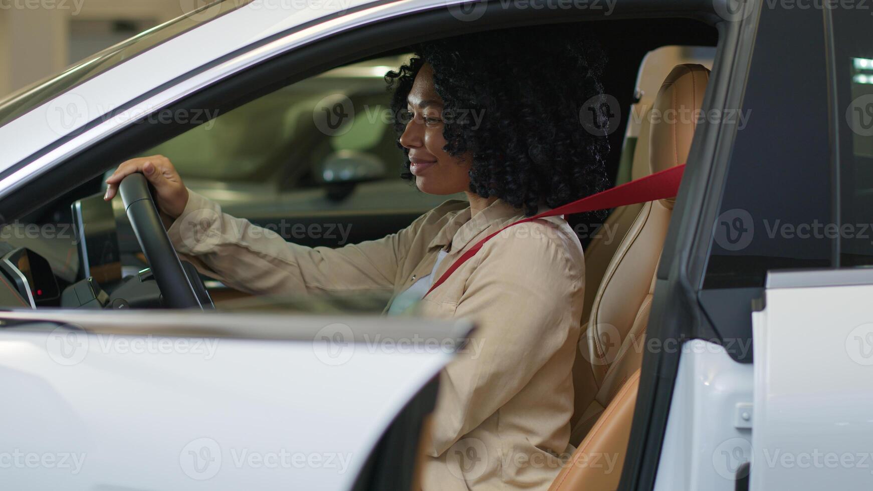 Happy African American woman sit on driver seat inside car smiling girl buyer turning steering wheel dreaming buying new transport in auto showroom choosing automobile test drive in dealership indoors photo