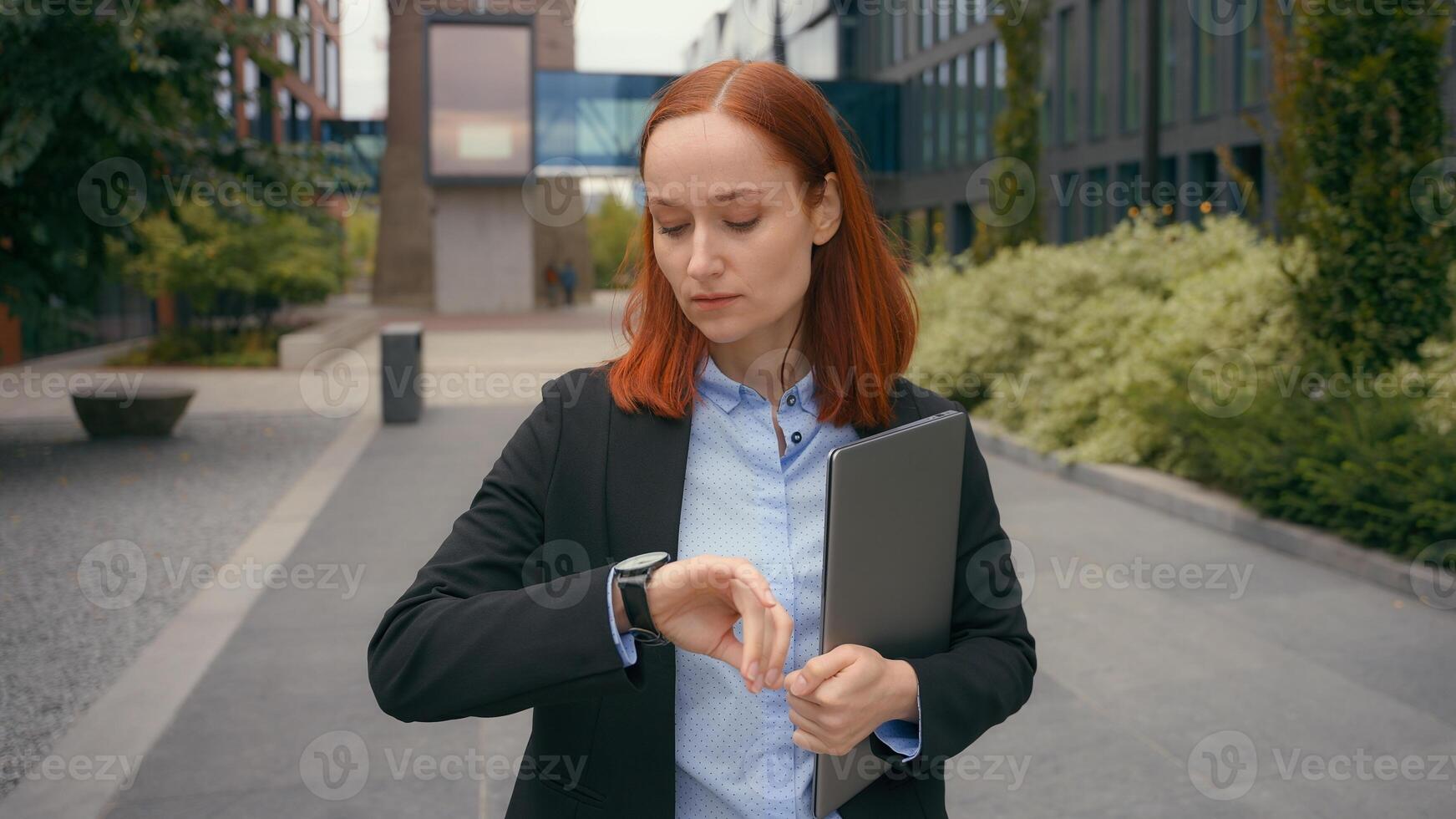 Caucasian businesswoman waiting meeting check time looking at wrist watch business woman wait in city outdoors near office company building sad female manager checking late clock lateness go away photo
