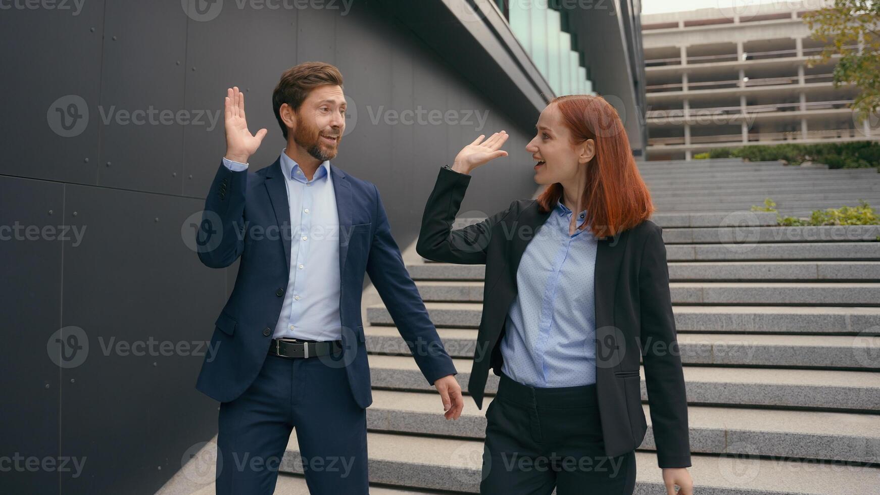 Caucasian business entrepreneurs walk success achievement gesture good idea agreement two people walking in city discuss colleagues coworkers man woman talking give high five smiling happy teamwork photo