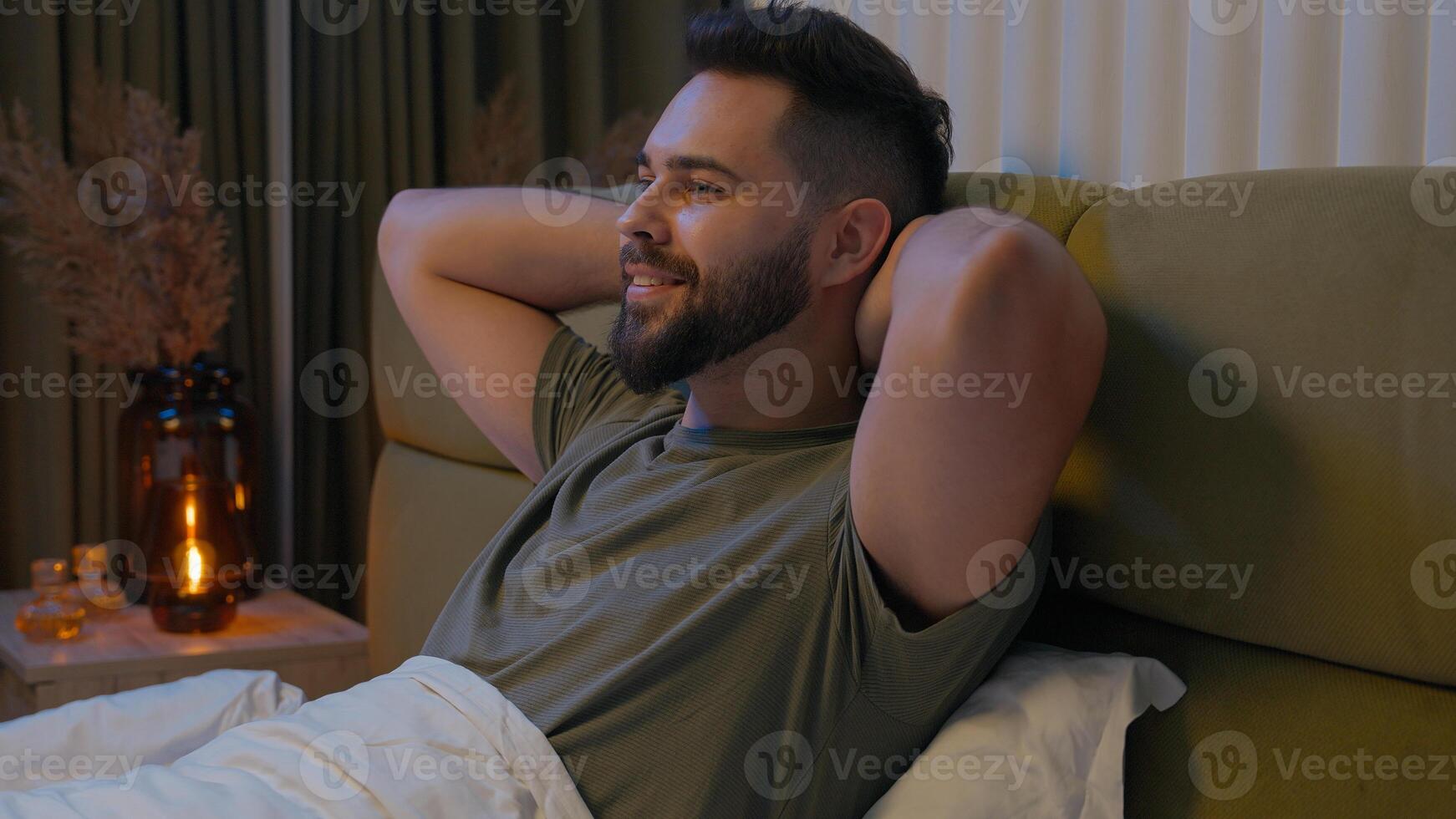 Happy Caucasian man prepare ready bed bedroom male relax cozy comfortable bedtime rest smiling pleasure apartment tenant duvet glad homeowner domestic enjoying hands behind head guy satisfaction sleep photo