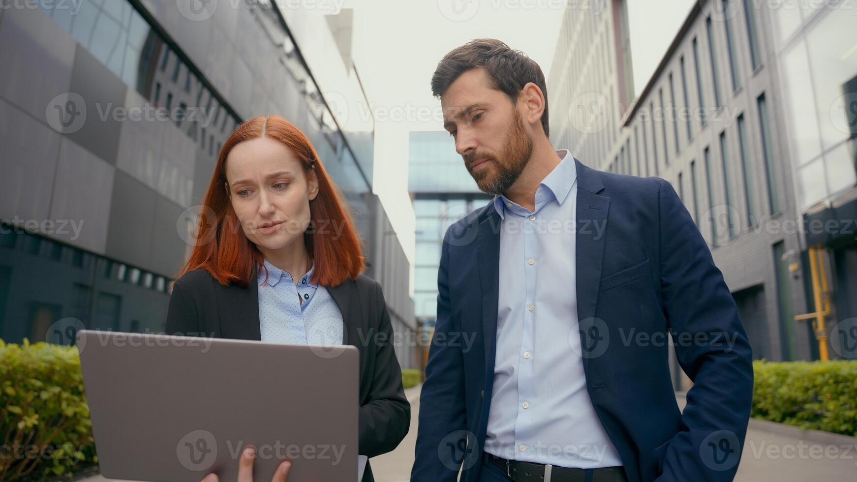 Caucasian businesswoman intern manager worker with laptop showing data leader businessman boss employer advice help talking together business partners colleagues with computer in city discuss deal photo