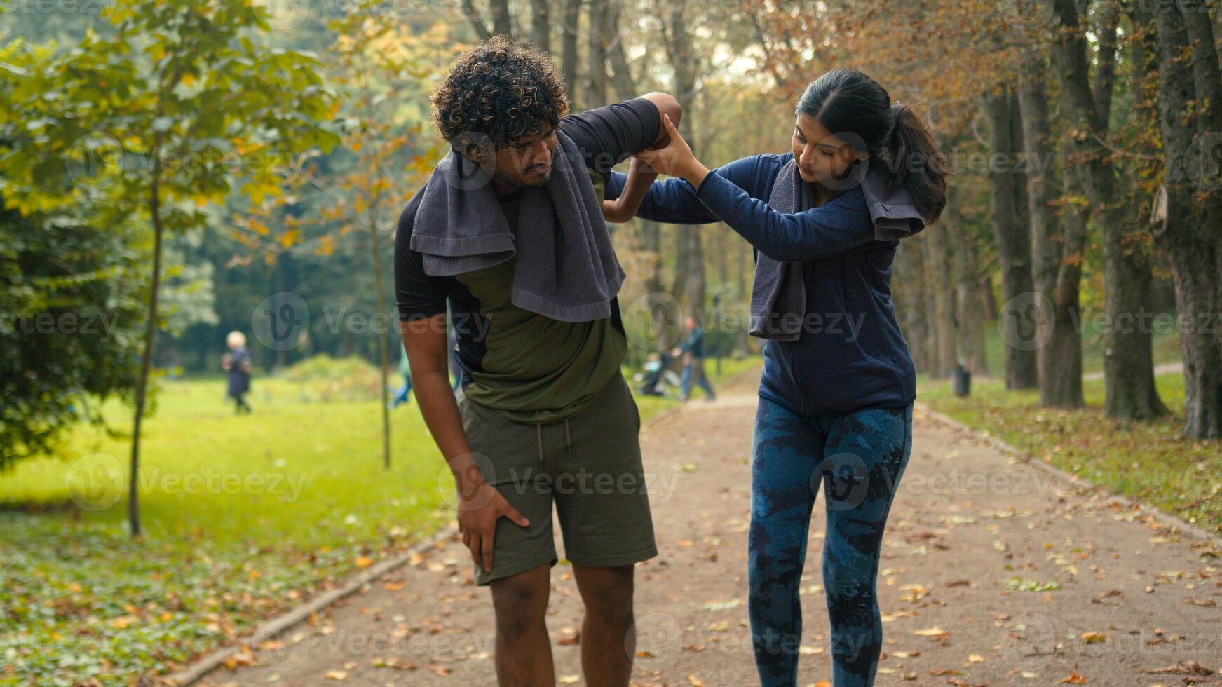 Outdoors in nature park Indian Arabian couple friends man woman stop after cardio fast run jog running man tired exhausted resting feel bad unwell pain ache girl calm support care of guy people sports photo