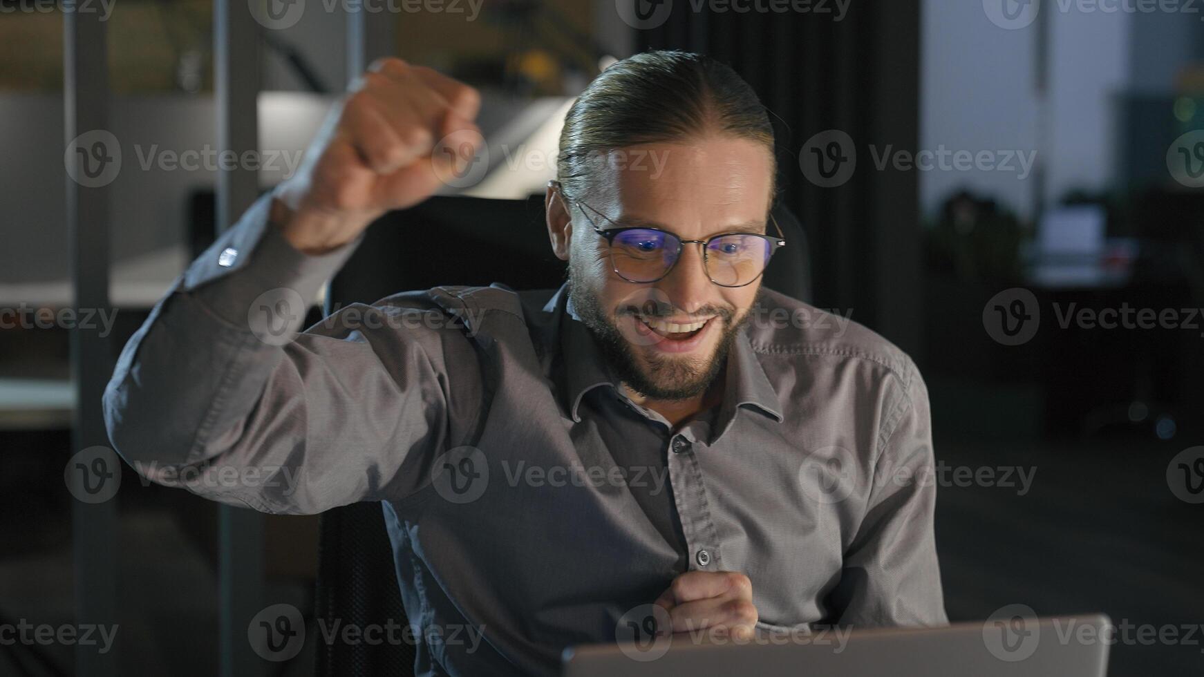 Excited rejoice Caucasian businessman looking at laptop shout scream with achievement computer triumph business man employer office worker winner hand gesture at night evening win achieve success photo