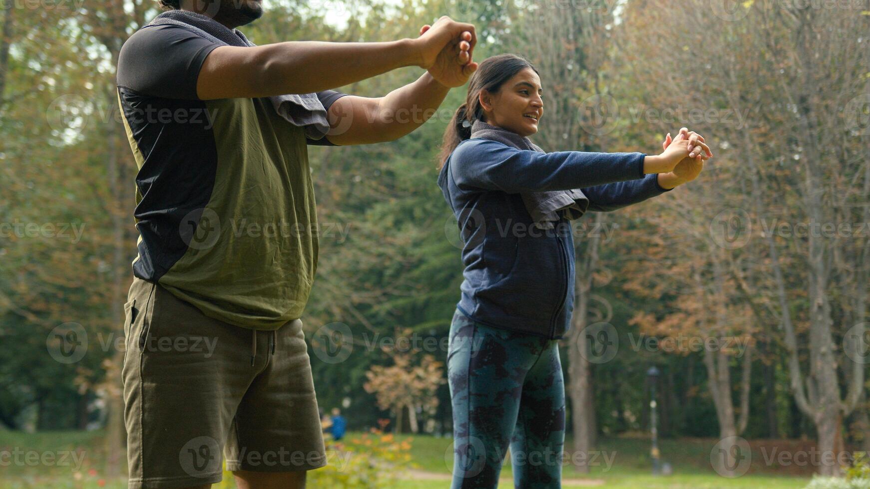 Slim motivated active sportive married people friends Indian couple sport squats workout exercise in park summer outdoors fit activity healthy lifestyle family together Arabian man woman squatting photo
