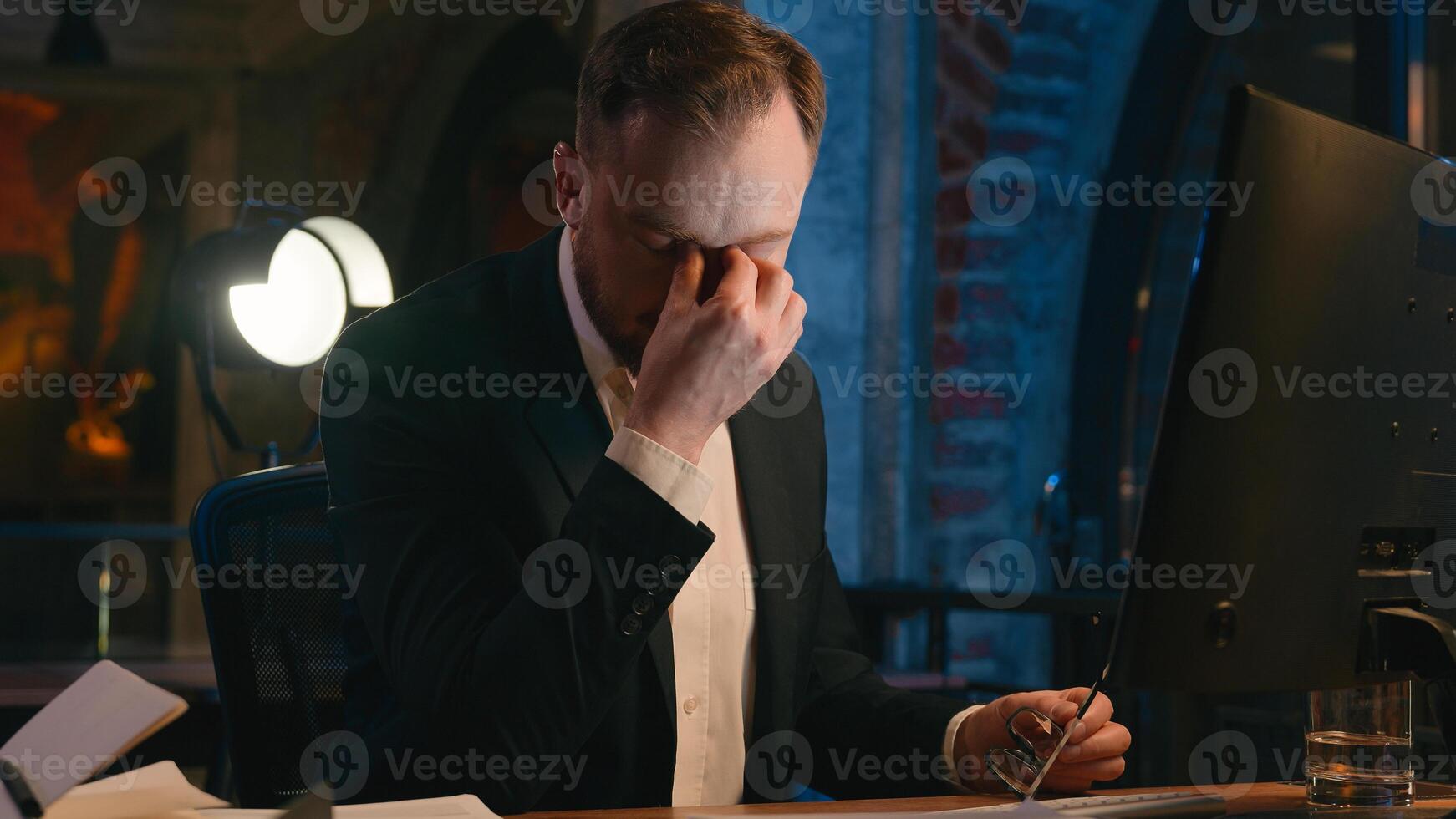 Caucasian businessman guy business man male working computer at night overtime office late time feel headache pain tired overworked health problem eyes strain take off glasses dry bad blurry eyesight photo