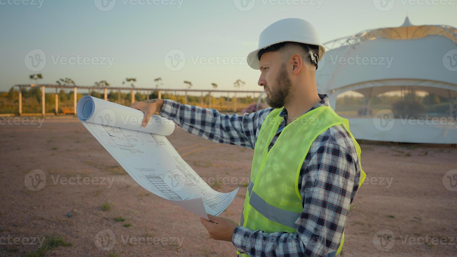 Pensive thoughtful professional Caucasian male man guy uniform engineer worker analysing reading project blueprint structure build plan confused inspector architect looking around farmland field park photo