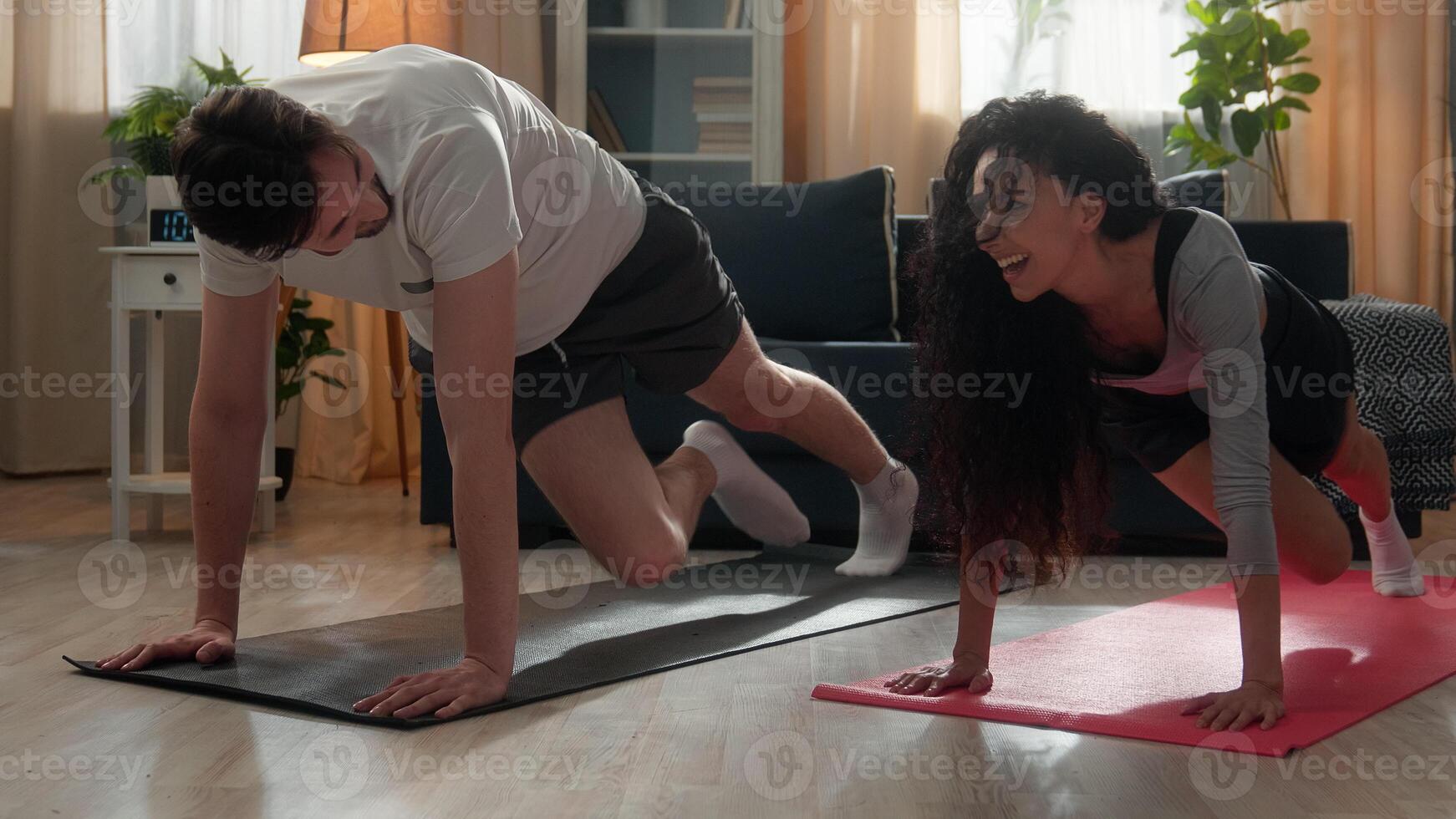Happy laughing couple tired family resting after hard cardio exercise workout Hispanic woman female fitness girl giving high five Caucasian guy man male relaxing celebrating sport achievement at home photo
