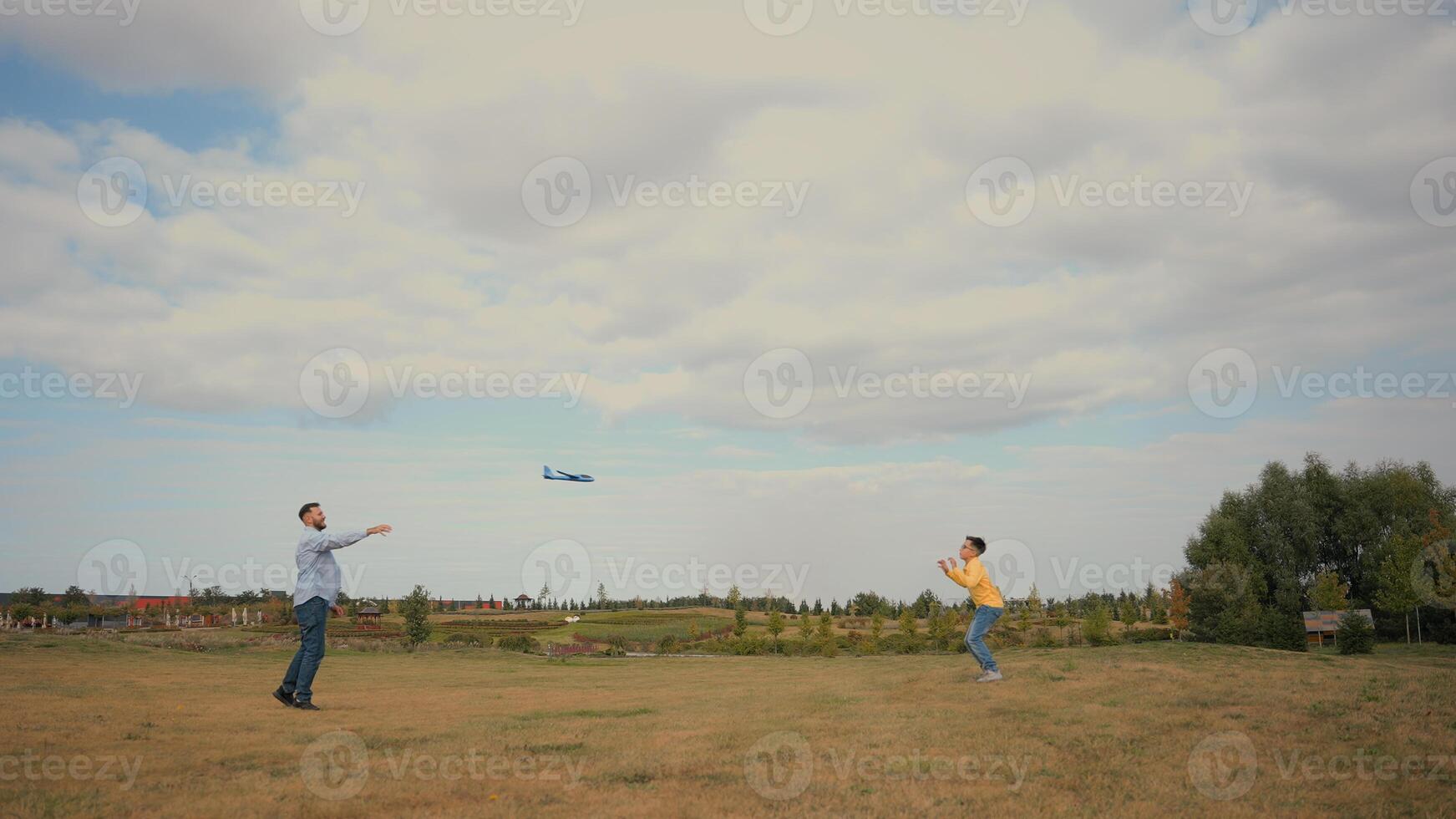 Happy Caucasian family father male man dad little boy son child kid schoolboy playing game throwing launching toy airplane plane enjoy activities together nature field meadow. Weekend trip fatherhood photo