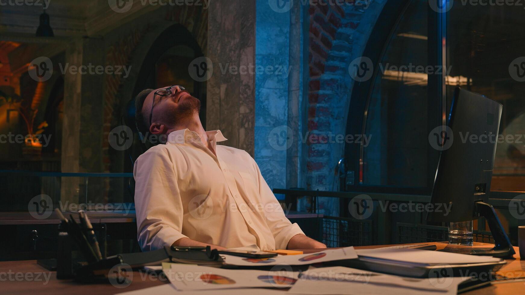 Caucasian man business guy businessman male workaholic in dark night office late time happy overtime insomnia overworked end off working computer satisfied finish online work complete job done relax photo