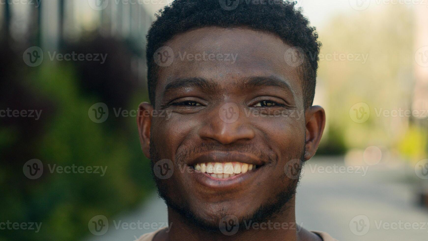 Closeup headshot African American cheerful positive happy smiling guy ethnic biracial man millennial male smile toothy white teeth dental service outdoors in city looking at camera student joyful face photo