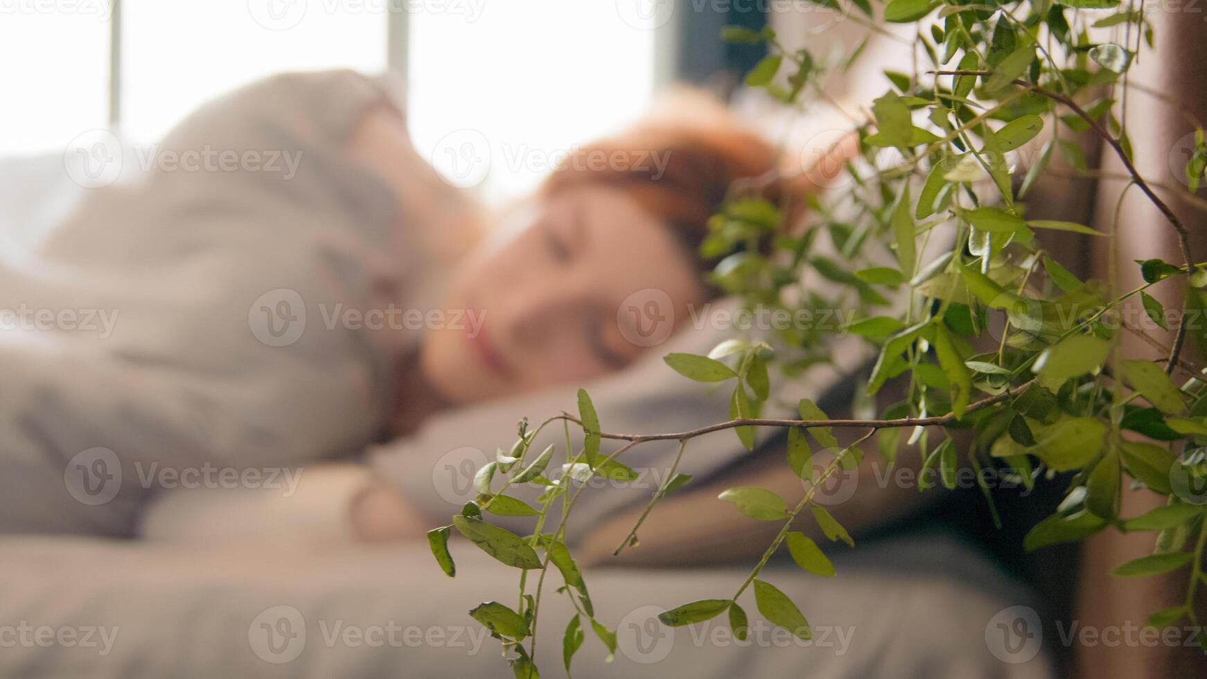 Close up Caucasian girl sleeping napping sleepy beautiful woman waking up lying in comfortable white bed looking at camera smiling lady happy smile after wake up female early morning in cozy bedroom photo