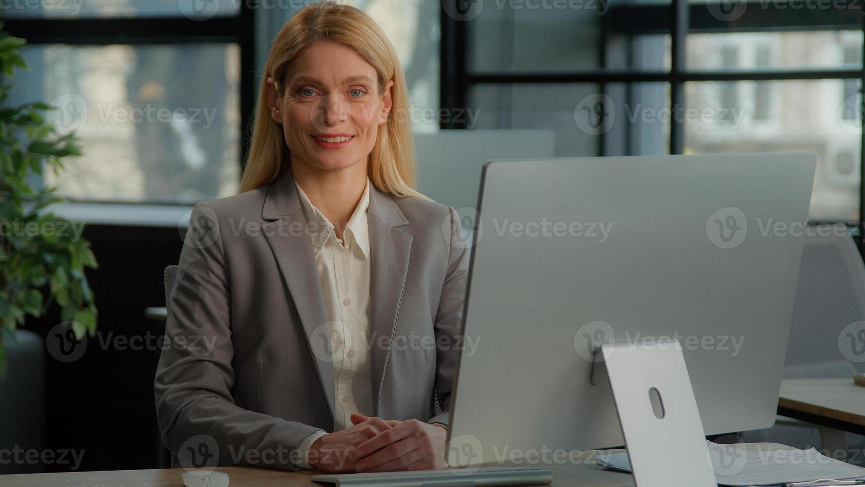 Smiling female worker middle-aged businesswoman looking at camera smile posing in office at workplace with computer happy executive woman employer lady professional administrator manager portrait photo