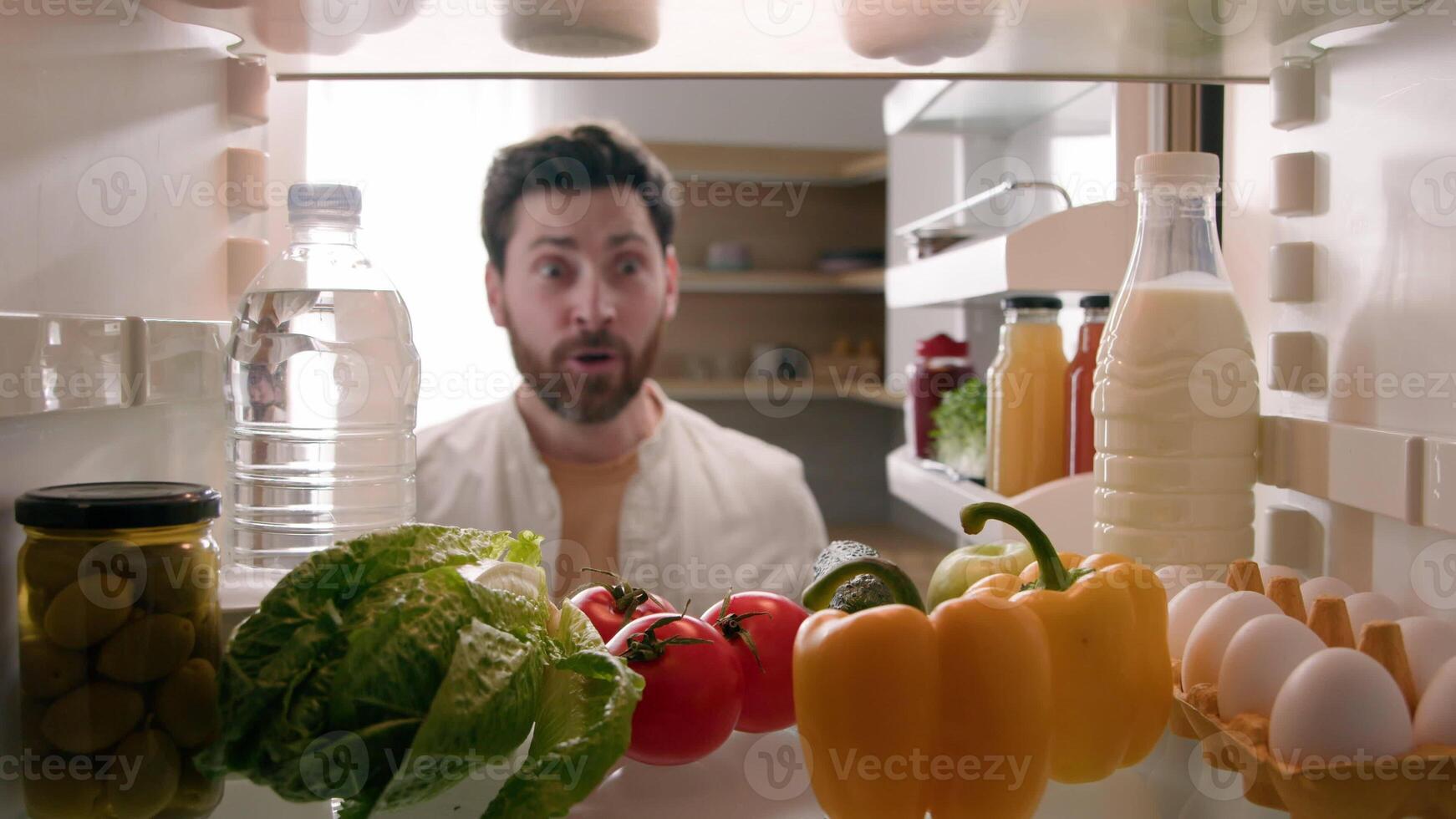 POV point of view from inside refrigerator Caucasian happy funny man adult excited surprised male guy looking in fridge with many food full of organic products say wow kiss tomato delivery supermarket photo