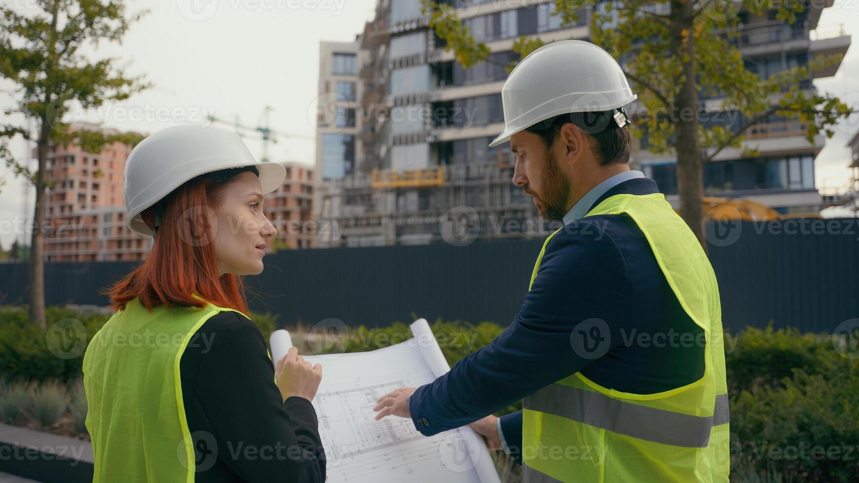 Two contractors civil engineers checking information in blueprint discuss teamwork pointing city buildings project managers planning collaboration construction workers with plan for urban development photo