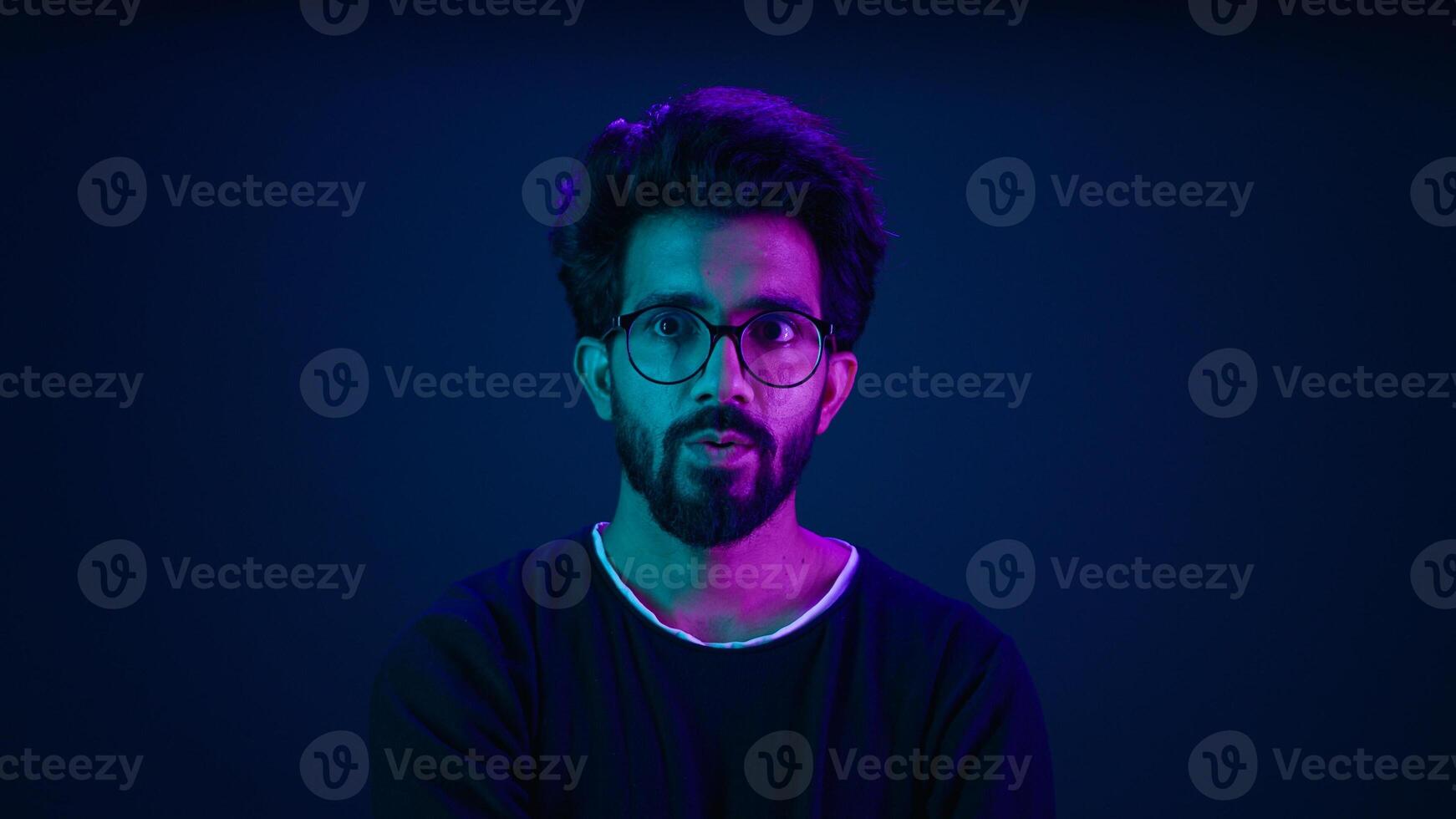 Male portrait neon background shocked amazed astonish wonder Indian man coder hacker computer technology worker guy looking in front futuristic high-tech software hologram mock up infographic backdrop photo