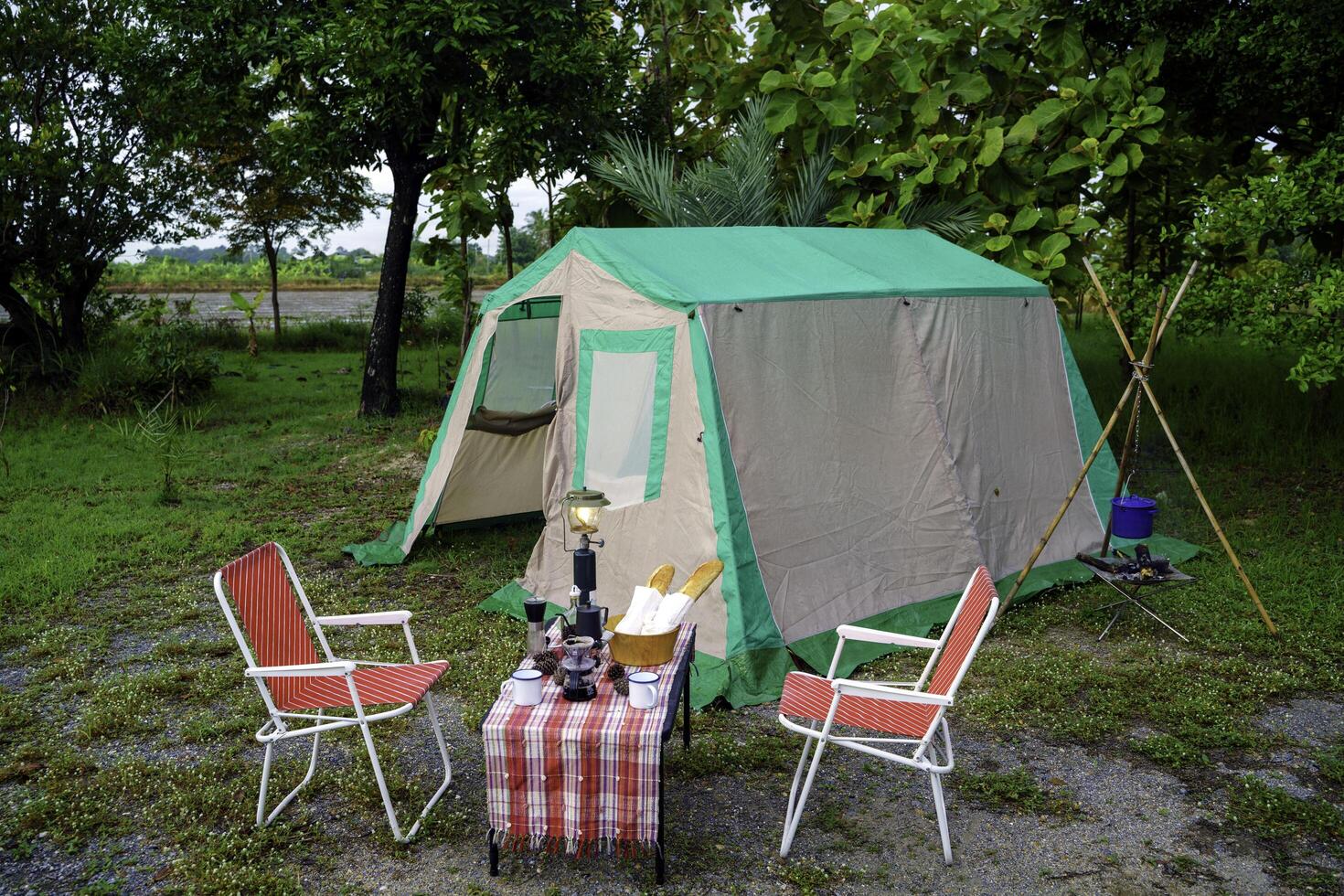 selective focus of vintage coffee set on the old wooden table In front of the retro cabin tent, retro chairs, Group of camping tents, and soft focus. photo
